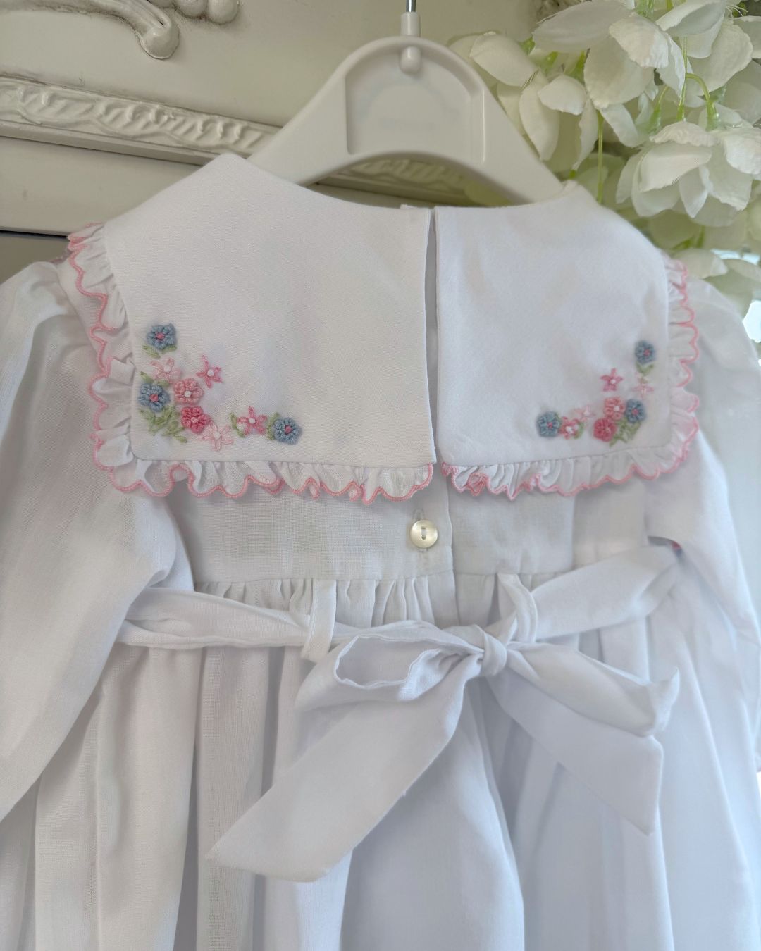 Sarah Louise Evelyn white girls smocked dress with pink and blue floral embroidery, square frill collar, satin bows and bow back tie.