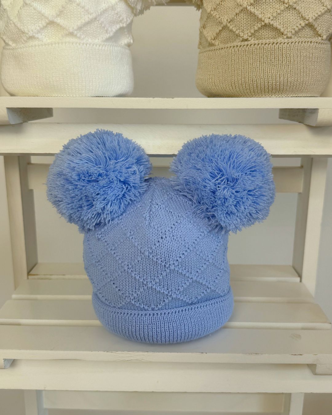 Little Nosh Hopscotch baby winter hat with double pom poms and patterned knit, available in white, biscuit brown and soft blue.