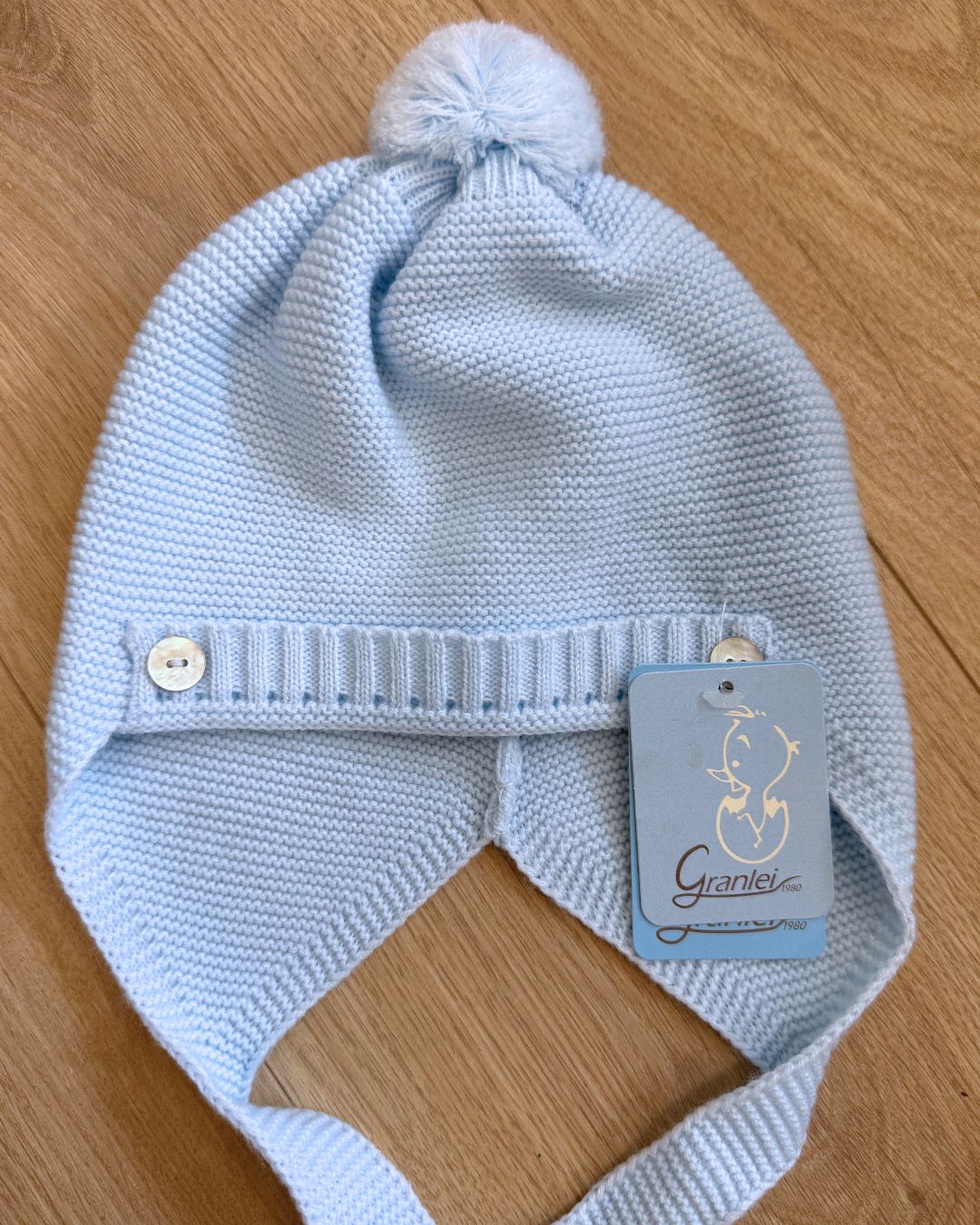 Granlei celeste blue knitted baby boys pom hat with ties and button detailing.