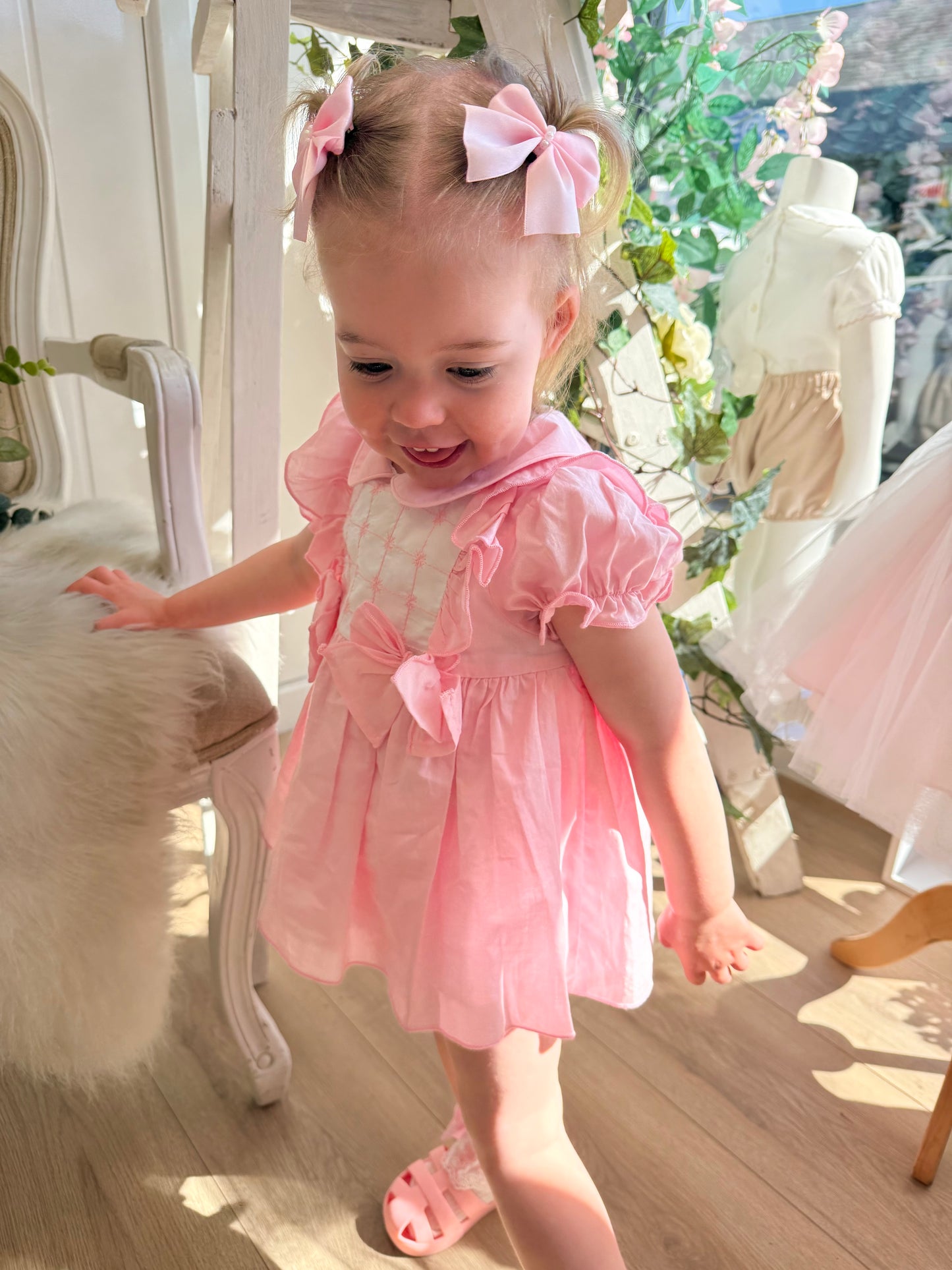 A soft rosy pink, this traditional Spanish-style dress is paired with matching jam pants. Adorned with a white chest panel featuring subtle stitch detailing, the dress is finished with pretty shoulder frills, two bow accents and a classic Peter Pan collar.