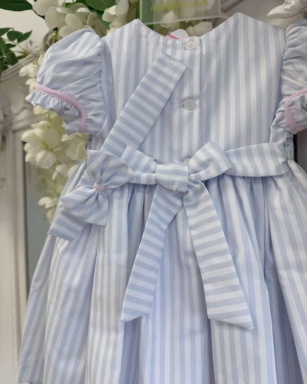 Pretty Originals Olivia Stripe Dress featuring blue and white stripes, hand-smocked rainbow embroidery, puff sleeves, matching bloomers and headband.