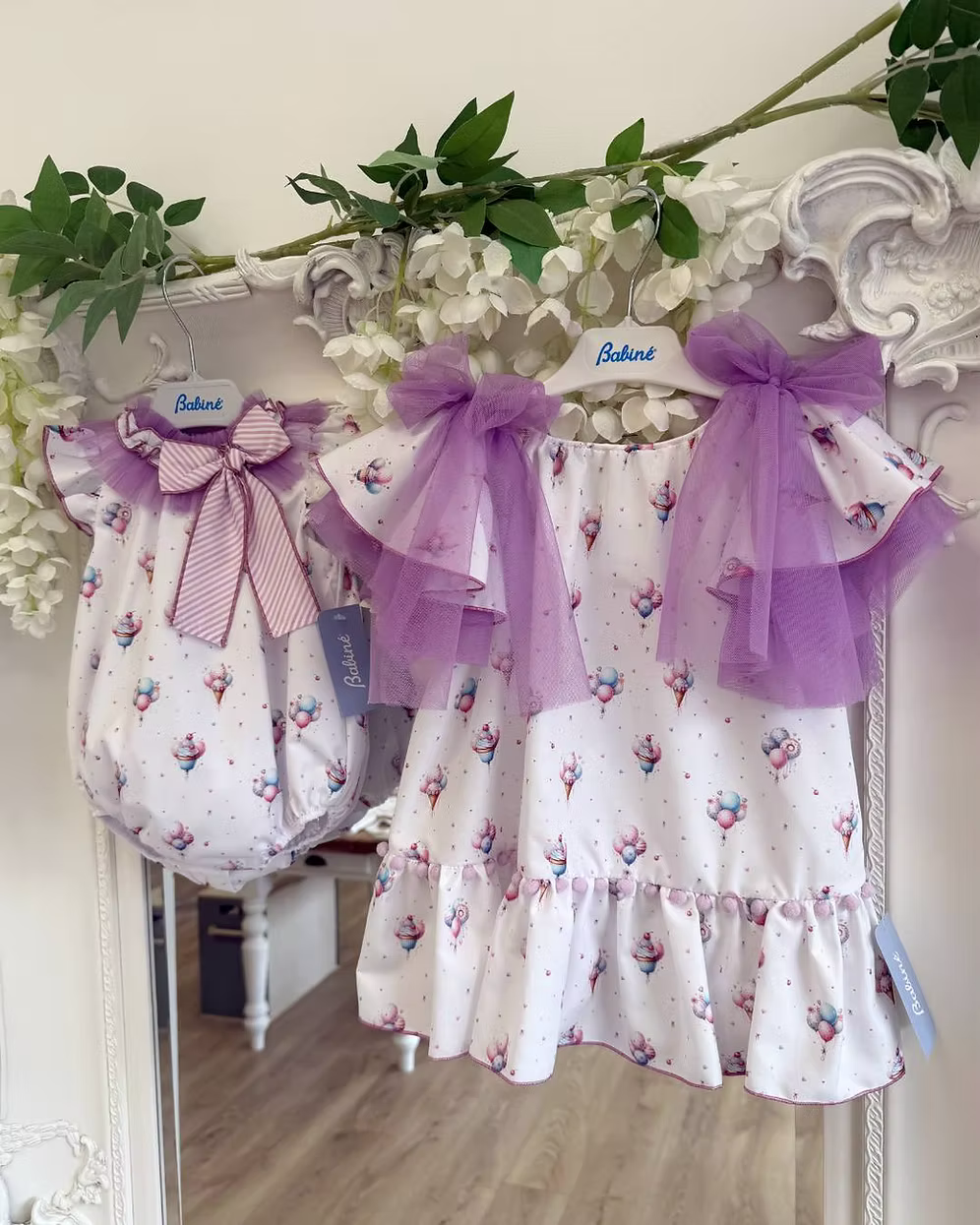 Babine Lilac Dream Dress featuring an ice cream, balloon and cupcake print, lilac tulle bows, frill sleeves, pom pom hem trim and scoop back tie.