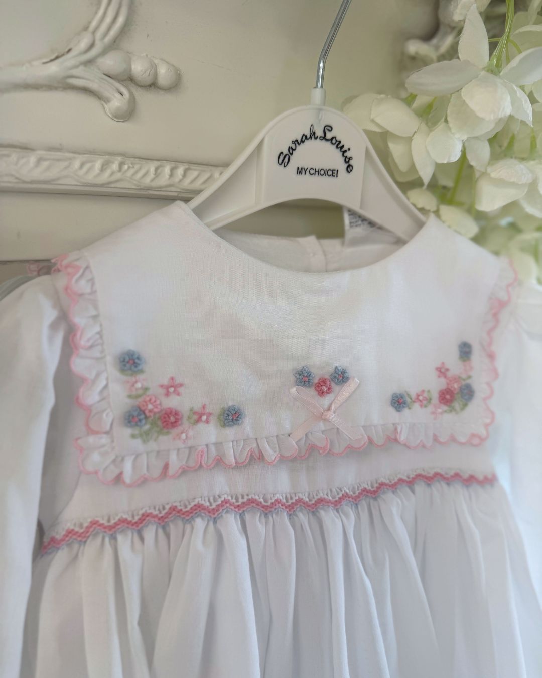 Sarah Louise Evelyn white girls smocked dress with pink and blue floral embroidery, square frill collar, satin bows and bow back tie.