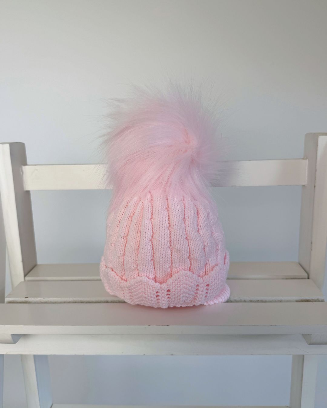 Little Nosh Aurora pink knitted baby girls winter hat with faux fur pom pom, scalloped hem and cosy ear covers.