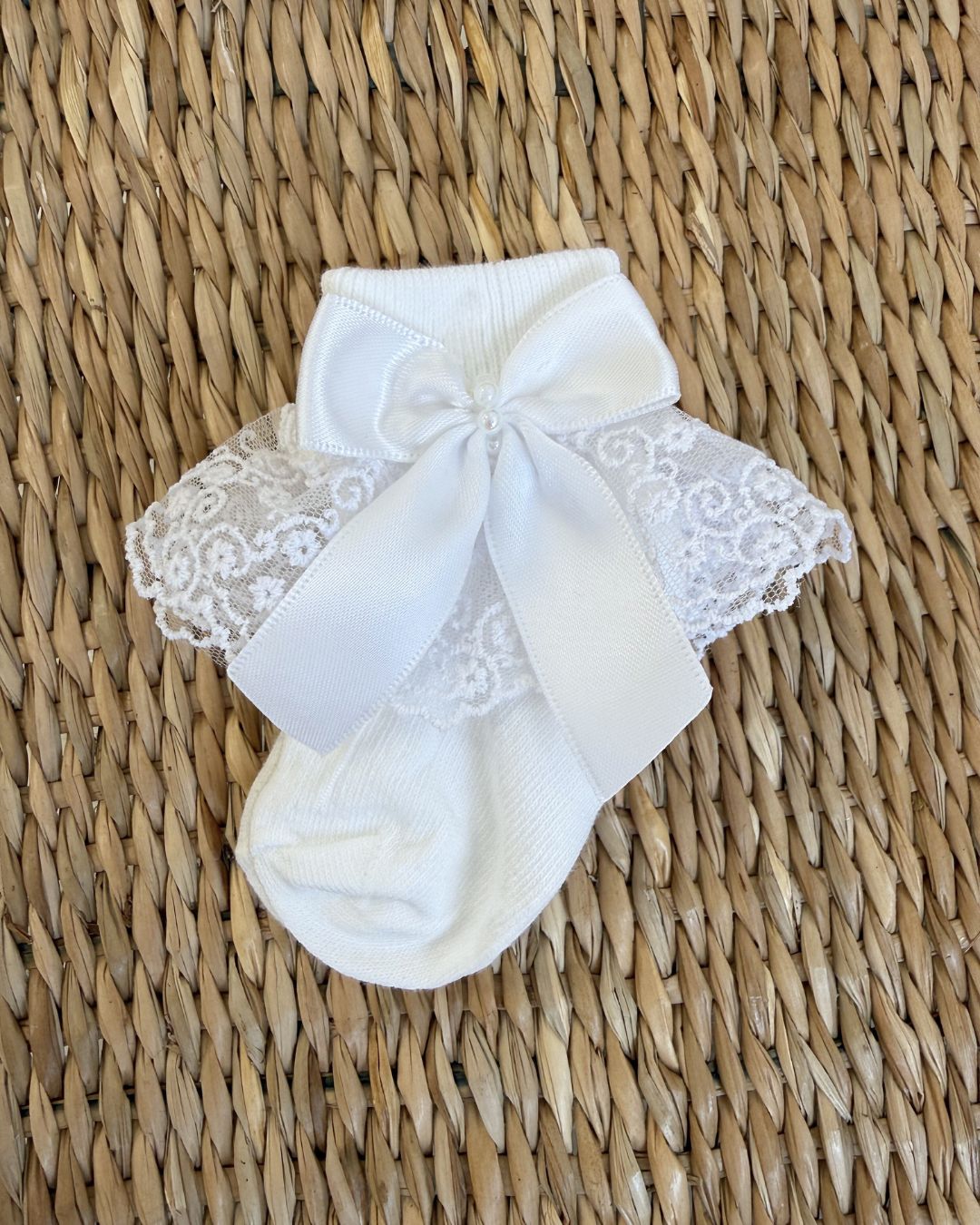 Crafted in soft white fabric, each pair features a delicate lace frill trim, finished with a pretty satin side bow and elegant pearl chain centre.