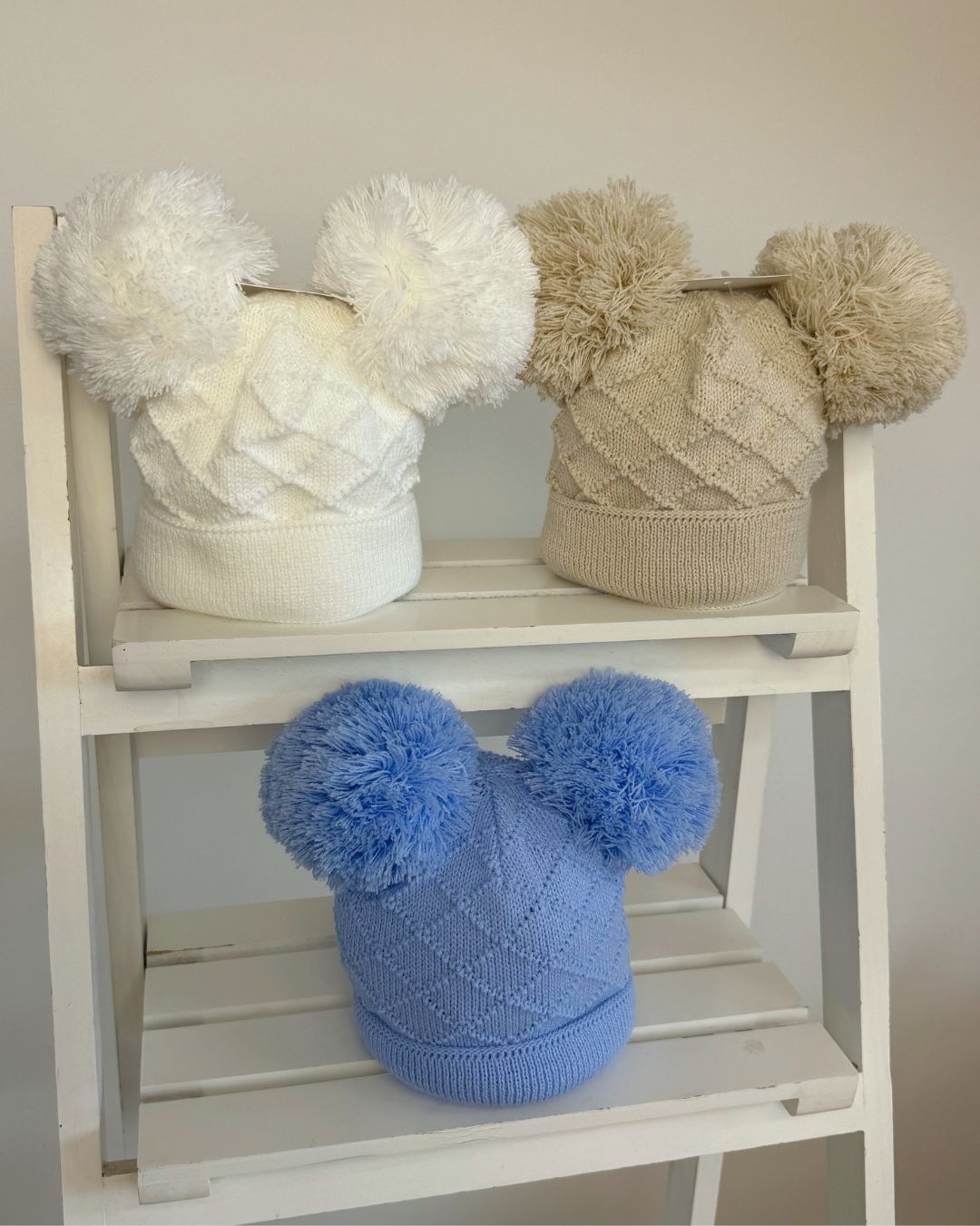 Little Nosh Hopscotch baby winter hat with double pom poms and patterned knit, available in white, biscuit brown and soft blue.