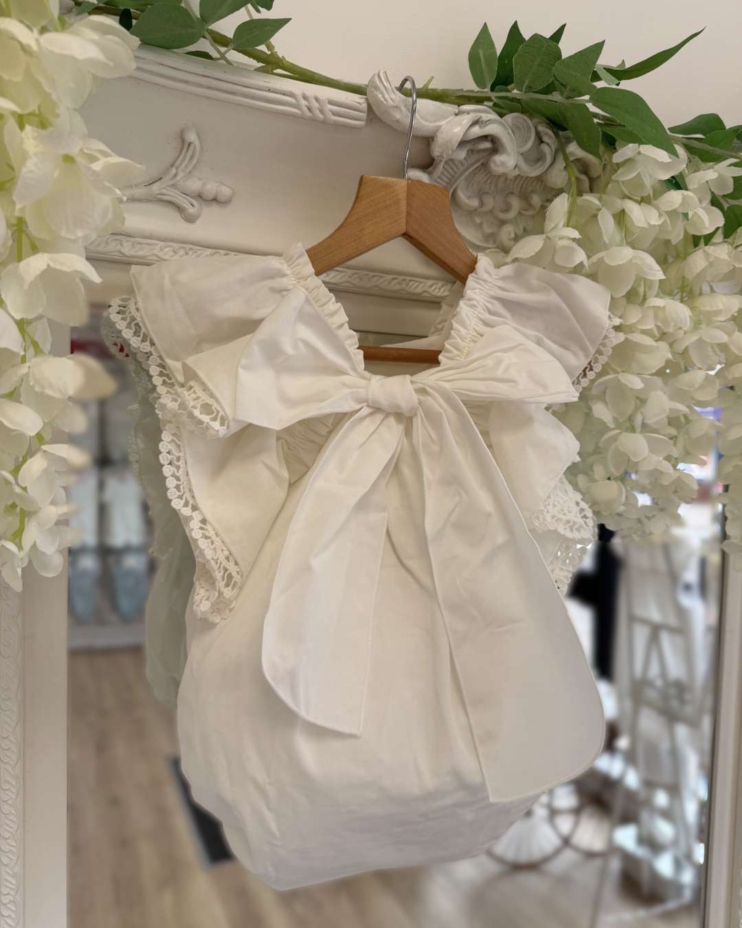 Phi Ivy Bow Back Romper featuring soft ivory cotton, lace-trimmed frill sleeves and an oversized statement bow at the back.