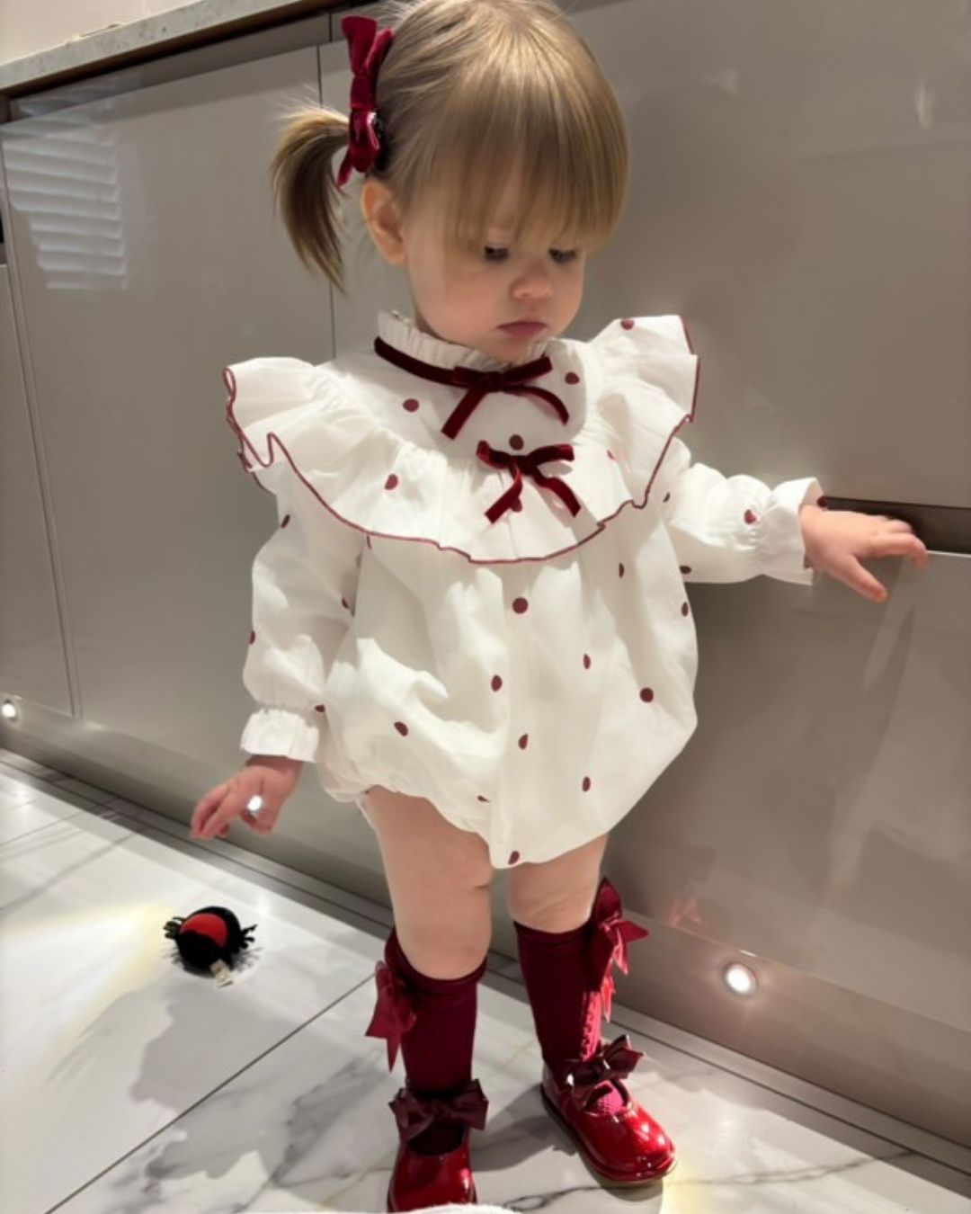 Phi Juliet ivory baby girls romper with red polka dots, frilled collar and red velvet bows.