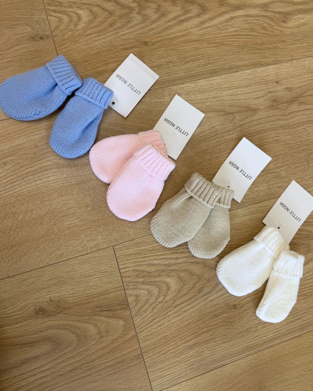Little Nosh knitted baby winter mittens with turnover cuffs, available in white, pink, biscuit brown and blue.
