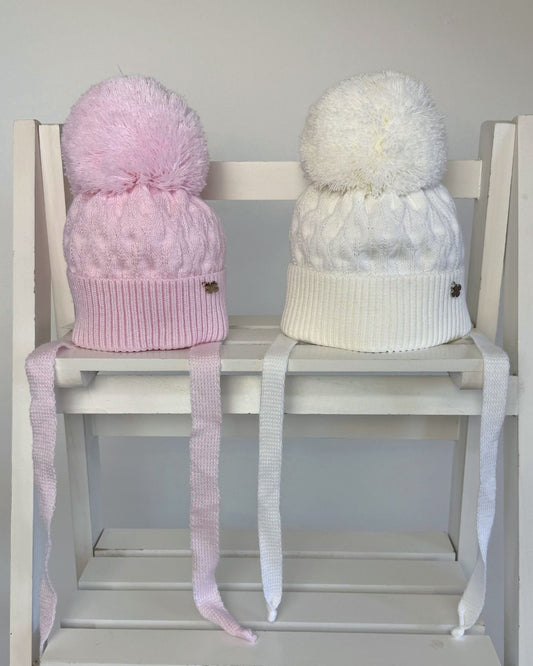 Jamiks Belinda cable knit baby pom hat with chin ties, available in soft pink and white.