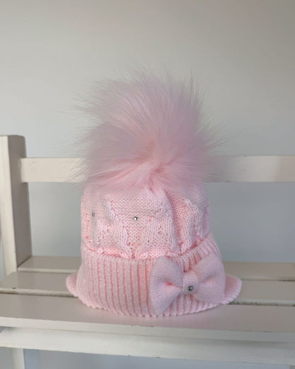 Little Nosh pink knitted girls’ winter hat with faux fur pom pom, bow, diamanté detailing and ear covers.