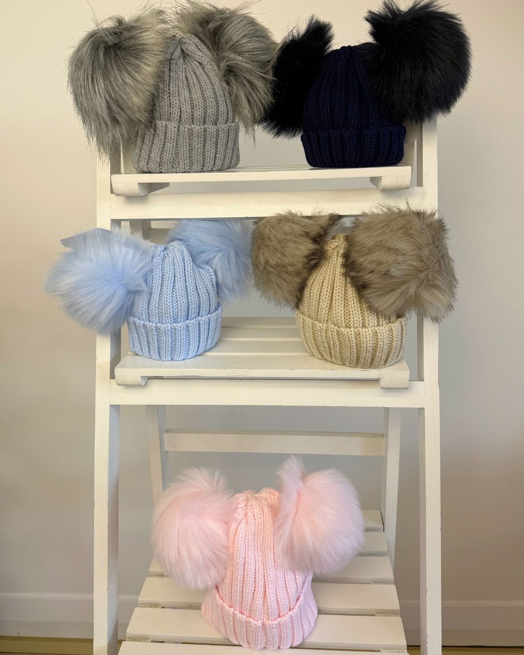 Kinder knitted double faux fur pom hats for babies and children in pink, baby blue, beige, grey and navy.