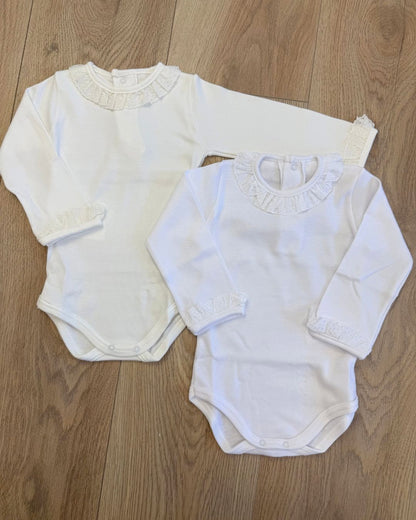 Calamaro long sleeve baby girls vest in white and ivory with a delicate broderie anglaise lace frill collar, matching frilled cuffs and popper fastenings.
