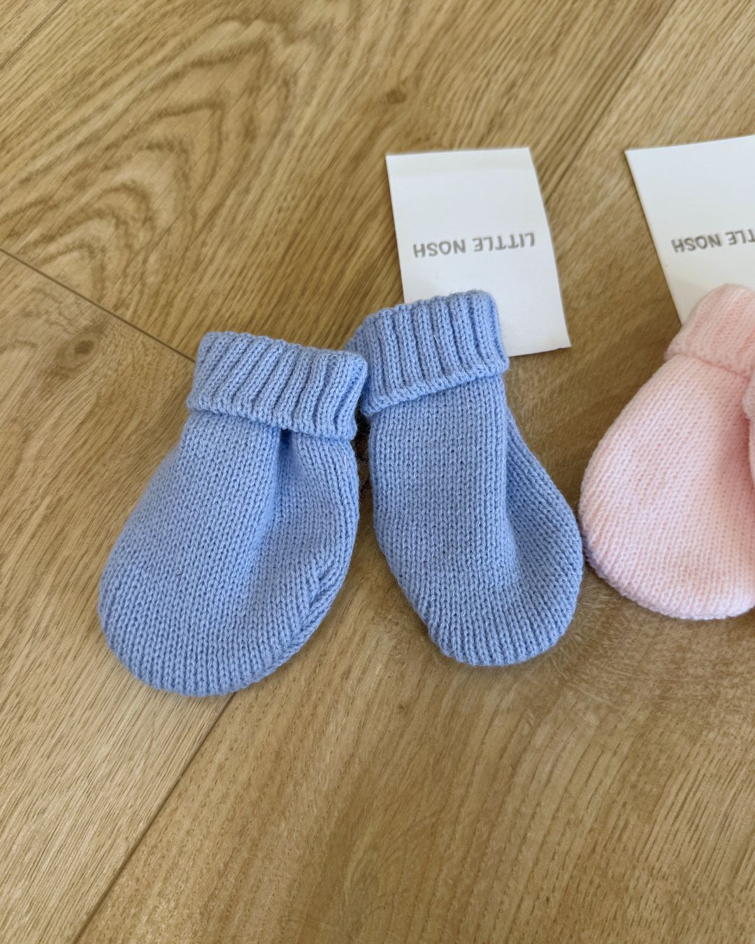 Little Nosh knitted baby winter mittens with turnover cuffs, available in white, pink, biscuit brown and blue.