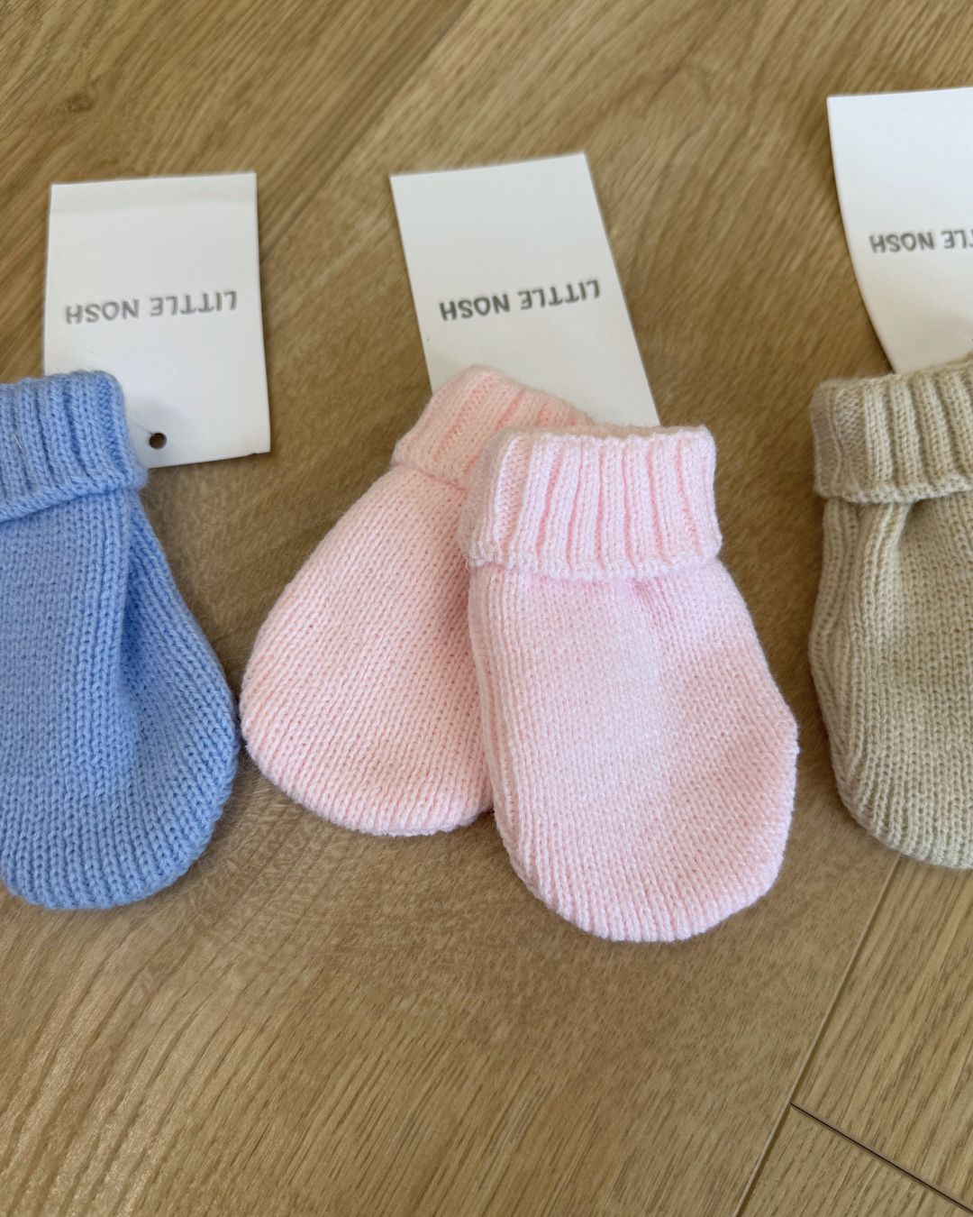 Little Nosh knitted baby winter mittens with turnover cuffs, available in white, pink, biscuit brown and blue.