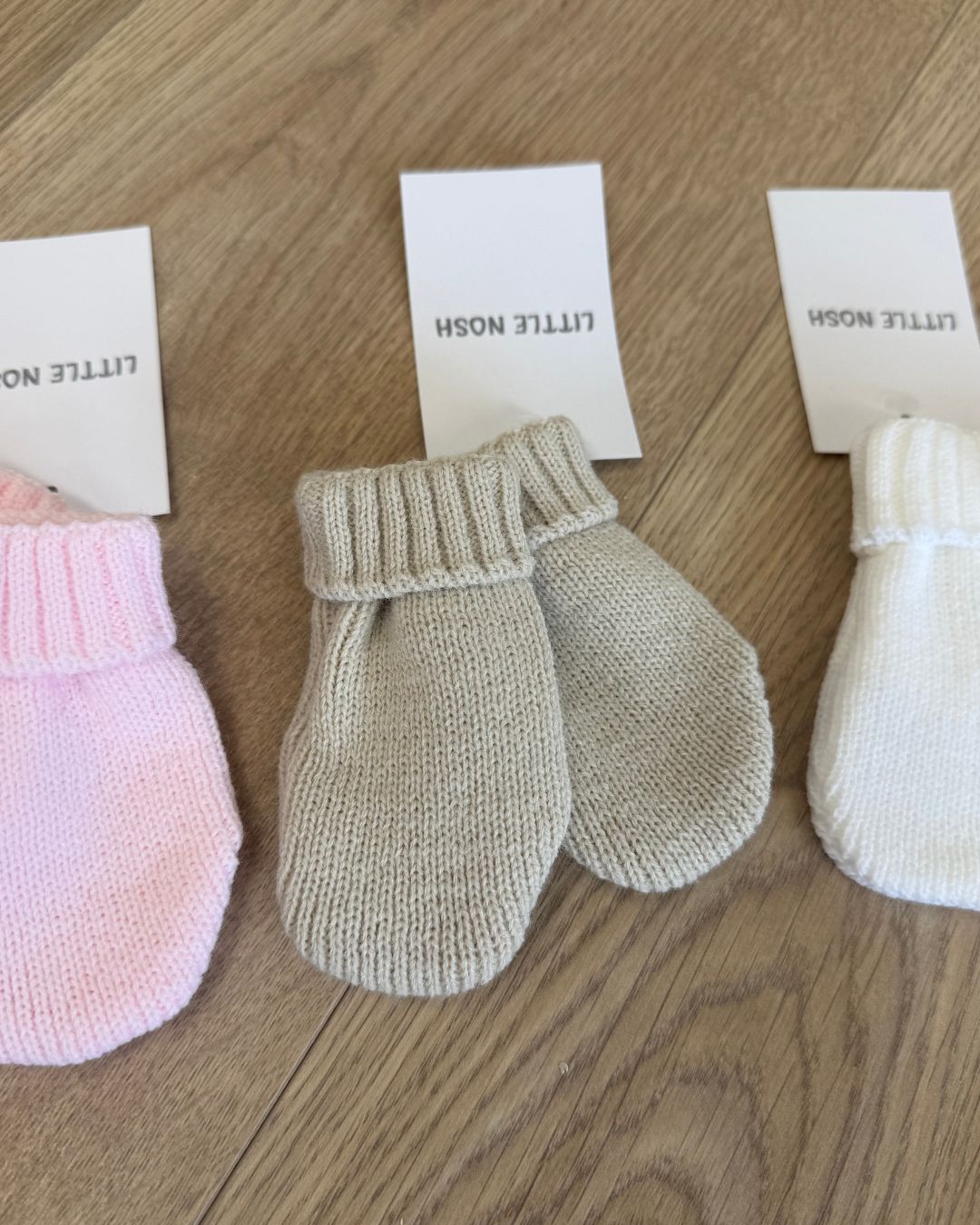 Little Nosh knitted baby winter mittens with turnover cuffs, available in white, pink, biscuit brown and blue.