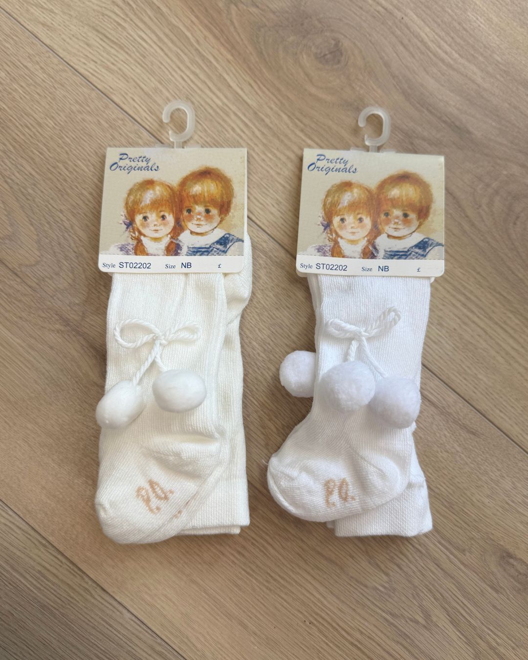 Pretty Originals unisex baby tights in white and ivory with soft pom pom detailing at the outer sides.