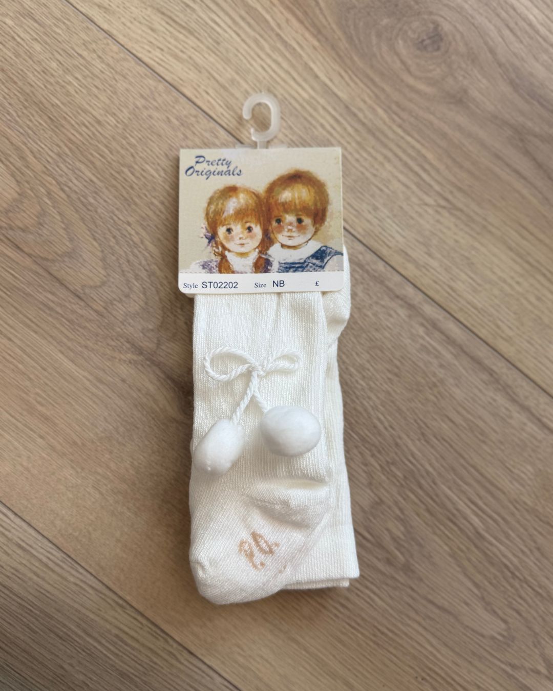 Pretty Originals unisex baby tights in white and ivory with soft pom pom detailing at the outer sides.