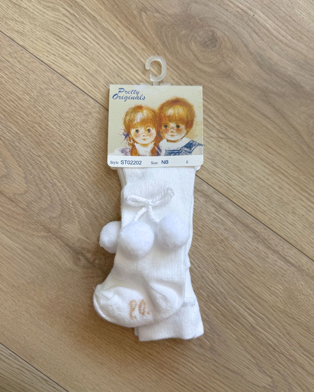 Pretty Originals unisex baby tights in white and ivory with soft pom pom detailing at the outer sides.