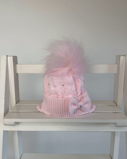 Little Nosh pink knitted girls’ winter hat with faux fur pom pom, bow, diamanté detailing and ear covers.