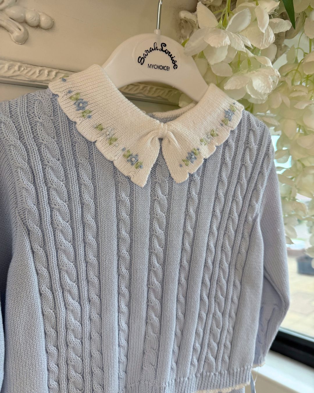 Sarah Louise Aster baby blue knitted trouser set with cable knit detailing and white floral embroidered collar.