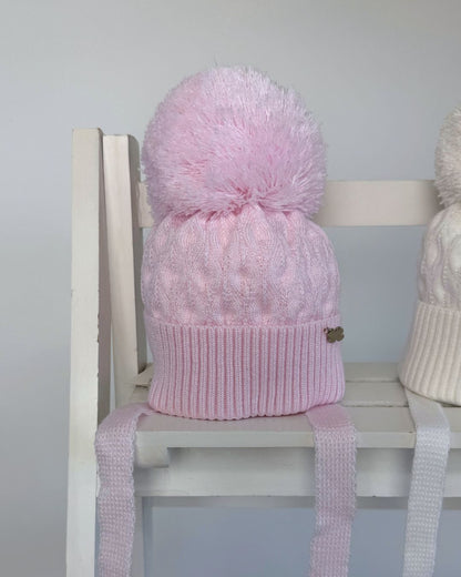 Jamiks Belinda cable knit baby pom hat with chin ties, available in soft pink and white.