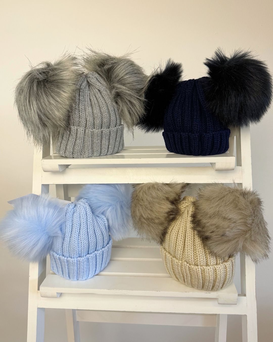 Kinder knitted double faux fur pom hats for babies and children in pink, baby blue, beige, grey and navy.