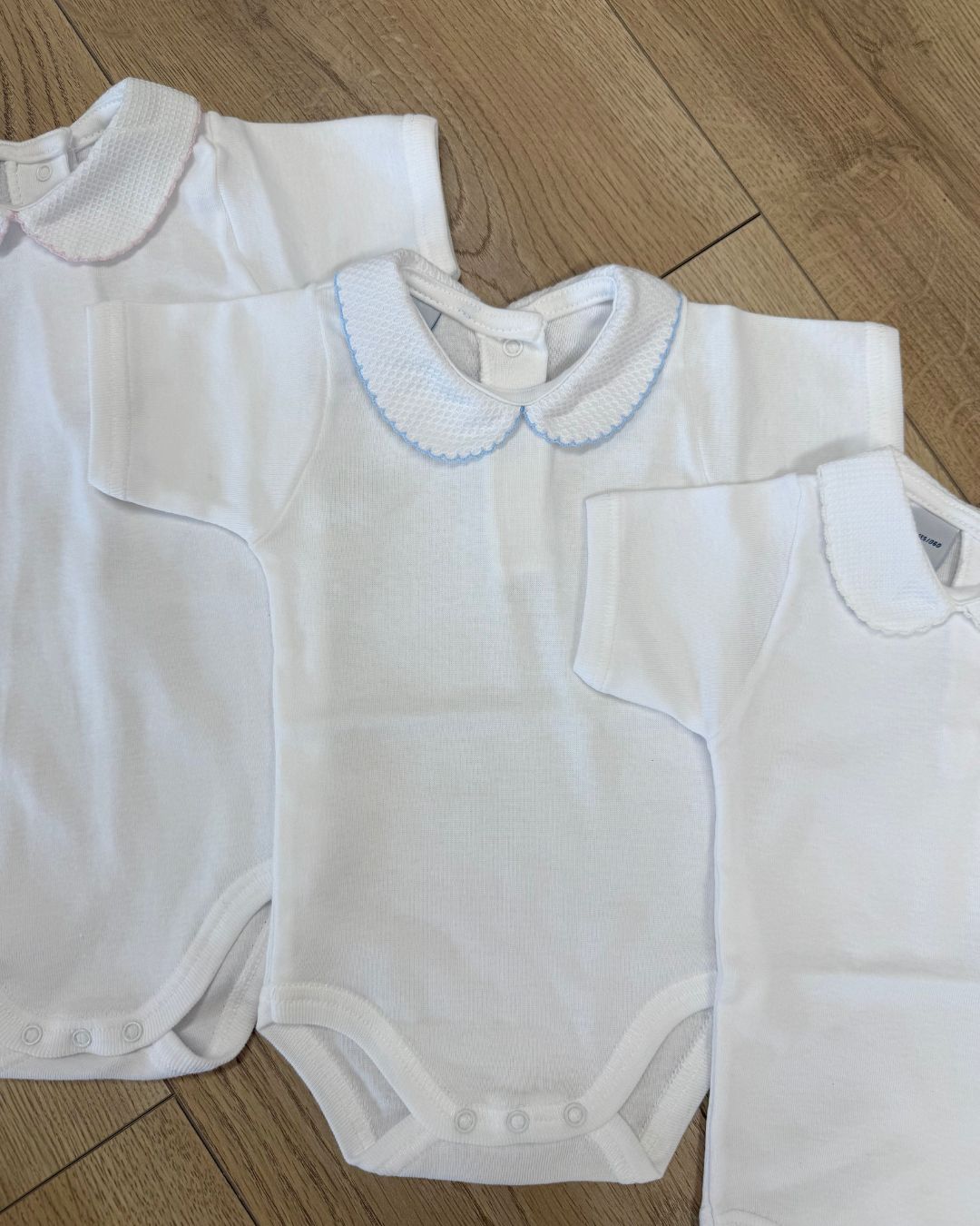 Babidu white unisex baby bodysuit with Peter Pan collar and coloured stitch trim.