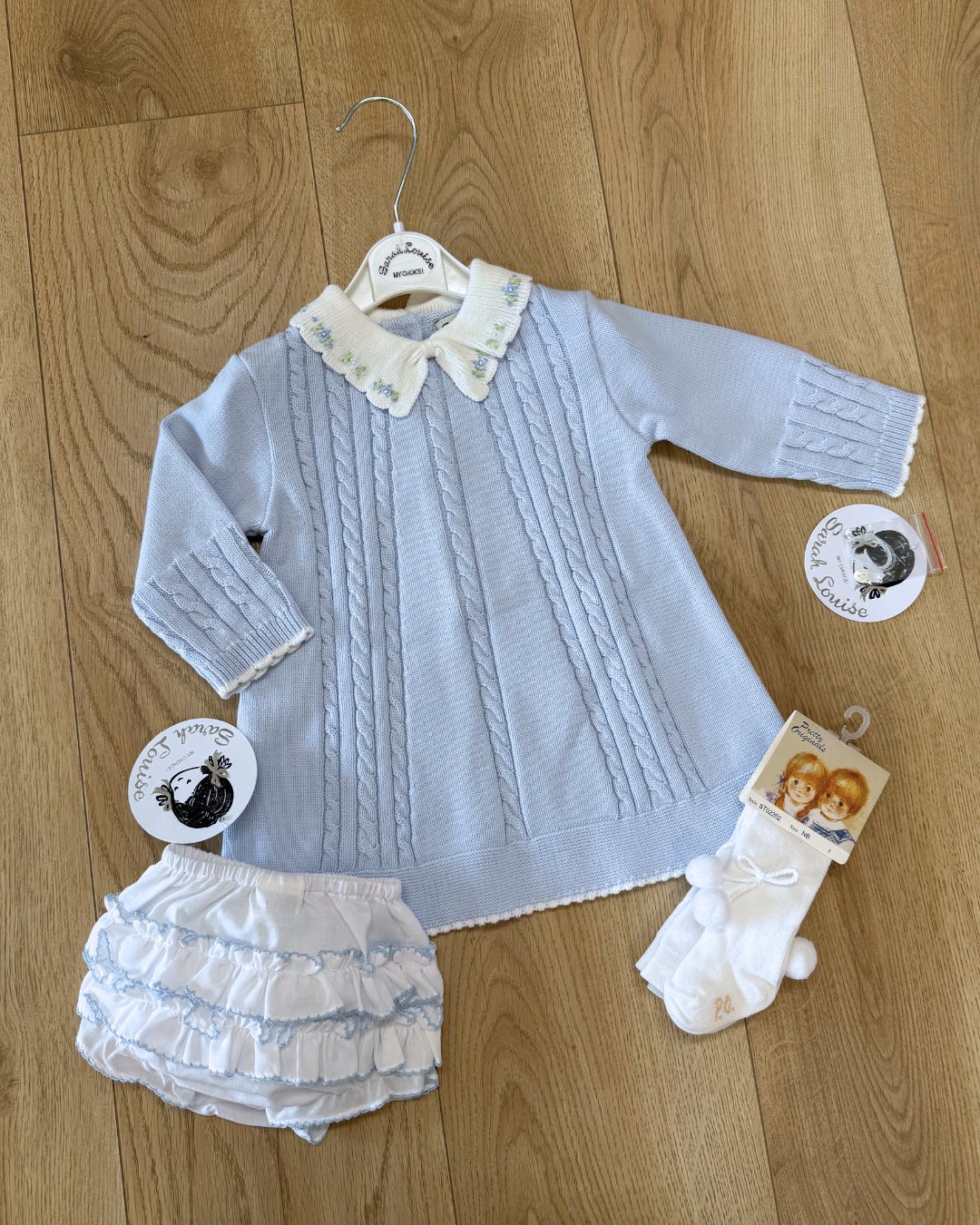 Sarah Louise Aster baby blue girls knitted dress with cable knit detailing, white scalloped floral embroidered collar and bow.