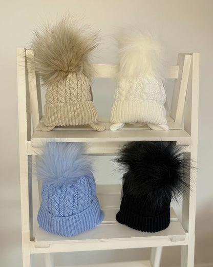 Little Nosh Topsy cable knit baby and children’s winter hat with faux fur pom pom, available in white, biscuit brown, blue and navy.