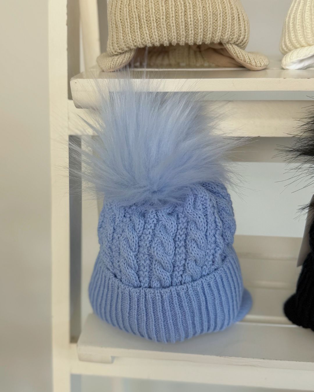 Little Nosh Topsy cable knit baby and children’s winter hat with faux fur pom pom, available in white, biscuit brown, blue and navy.
