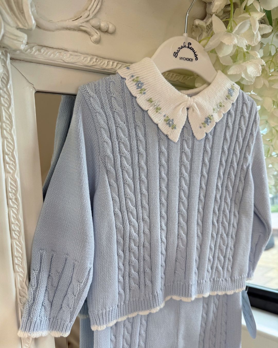 Sarah Louise Aster baby blue knitted trouser set with cable knit detailing and white floral embroidered collar.