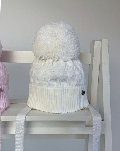 Jamiks Belinda cable knit baby pom hat with chin ties, available in soft pink and white.