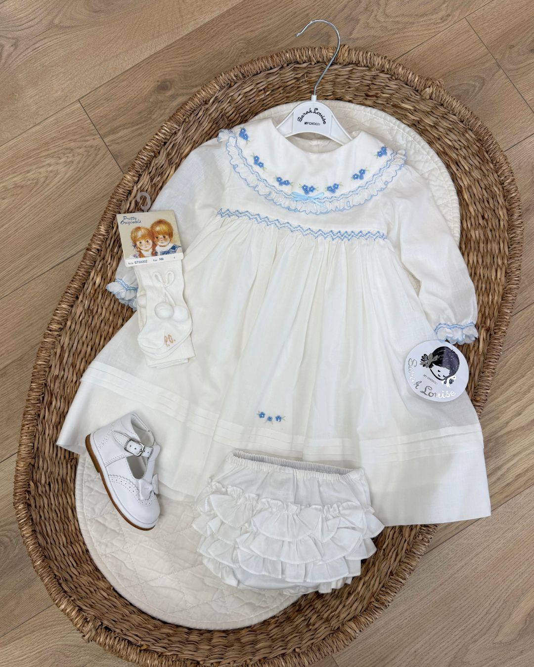 Sarah Louise Eleanor ivory girls smocked dress with blue floral embroidery, frilled collar, long sleeves and bow back tie.