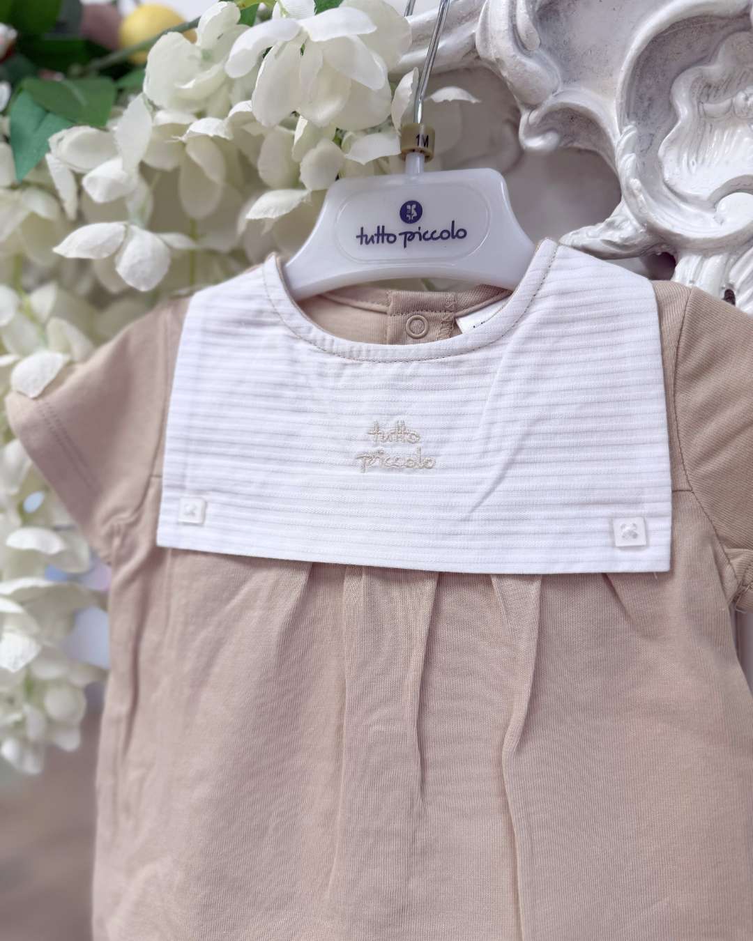 Tutto Piccolo Wren Romper featuring soft beige cotton, a striped bib-style collar, embroidered logo and classic pleated detailing.