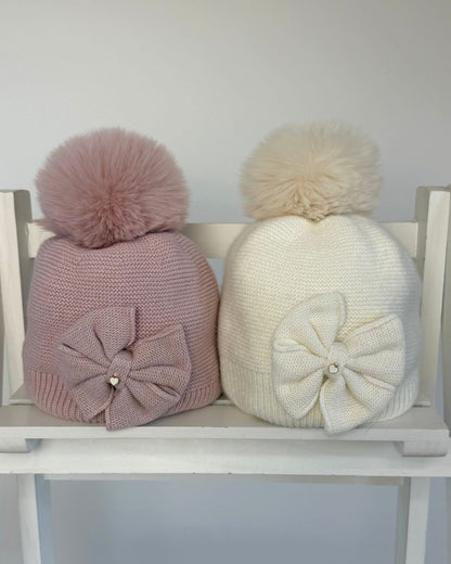 Jamiks Huntley girls knitted bow pom hat with faux fur pom pom, available in cream and dusty pink.