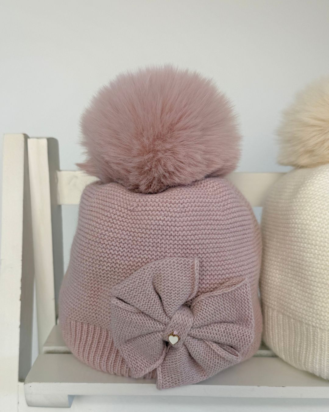Jamiks Huntley girls knitted bow pom hat with faux fur pom pom, available in cream and dusty pink.