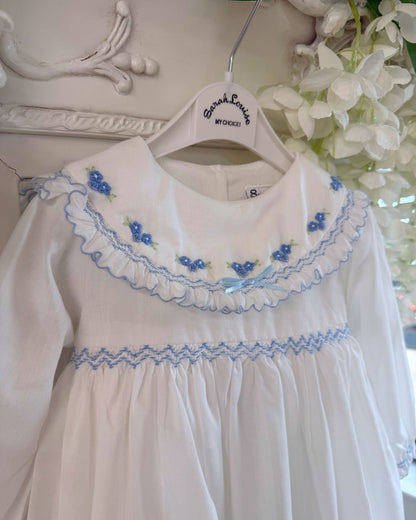 Sarah Louise Eleanor ivory girls smocked dress with blue floral embroidery, frilled collar, long sleeves and bow back tie.