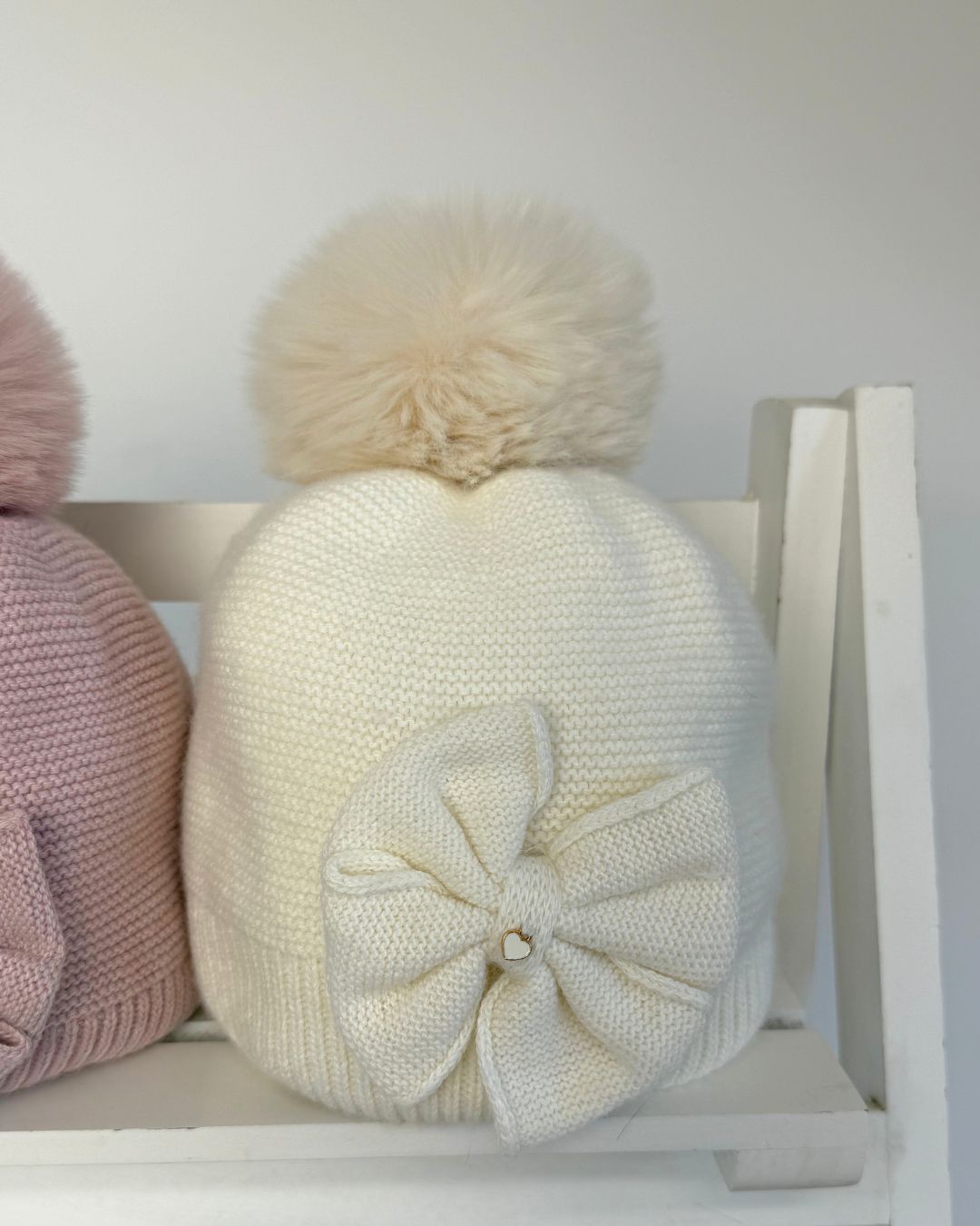 Jamiks Huntley girls knitted bow pom hat with faux fur pom pom, available in cream and dusty pink.