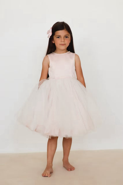 Sarah Louise Peach Pearl Ballerina Dress featuring a soft peach tone, pearl-trimmed neckline, full layered tulle skirt and statement V-back bow.