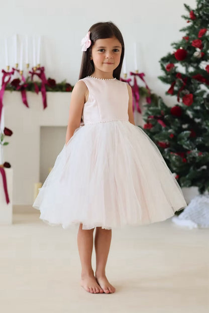 Sarah Louise Peach Pearl Ballerina Dress featuring a soft peach tone, pearl-trimmed neckline, full layered tulle skirt and statement V-back bow.