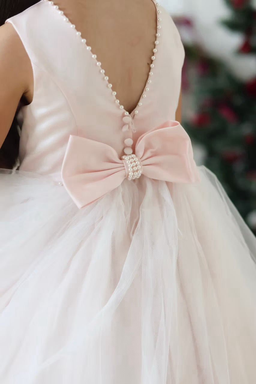 Sarah Louise Peach Pearl Ballerina Dress featuring a soft peach tone, pearl-trimmed neckline, full layered tulle skirt and statement V-back bow.
