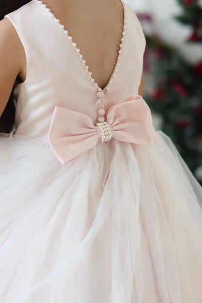 Sarah Louise Peach Pearl Ballerina Dress featuring a soft peach tone, pearl-trimmed neckline, full layered tulle skirt and statement V-back bow.
