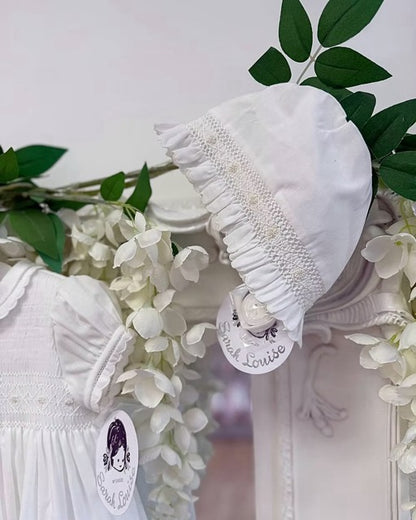Sarah Louise Philippa Christening Gown & Bonnet featuring hand-smocked floral embroidery, pearl details, scalloped trims and a matching bonnet.