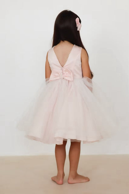 Sarah Louise Peach Pearl Ballerina Dress featuring a soft peach tone, pearl-trimmed neckline, full layered tulle skirt and statement V-back bow.