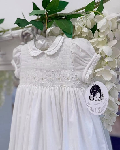 Sarah Louise Philippa Christening Gown & Bonnet featuring hand-smocked floral embroidery, pearl details, scalloped trims and a matching bonnet.