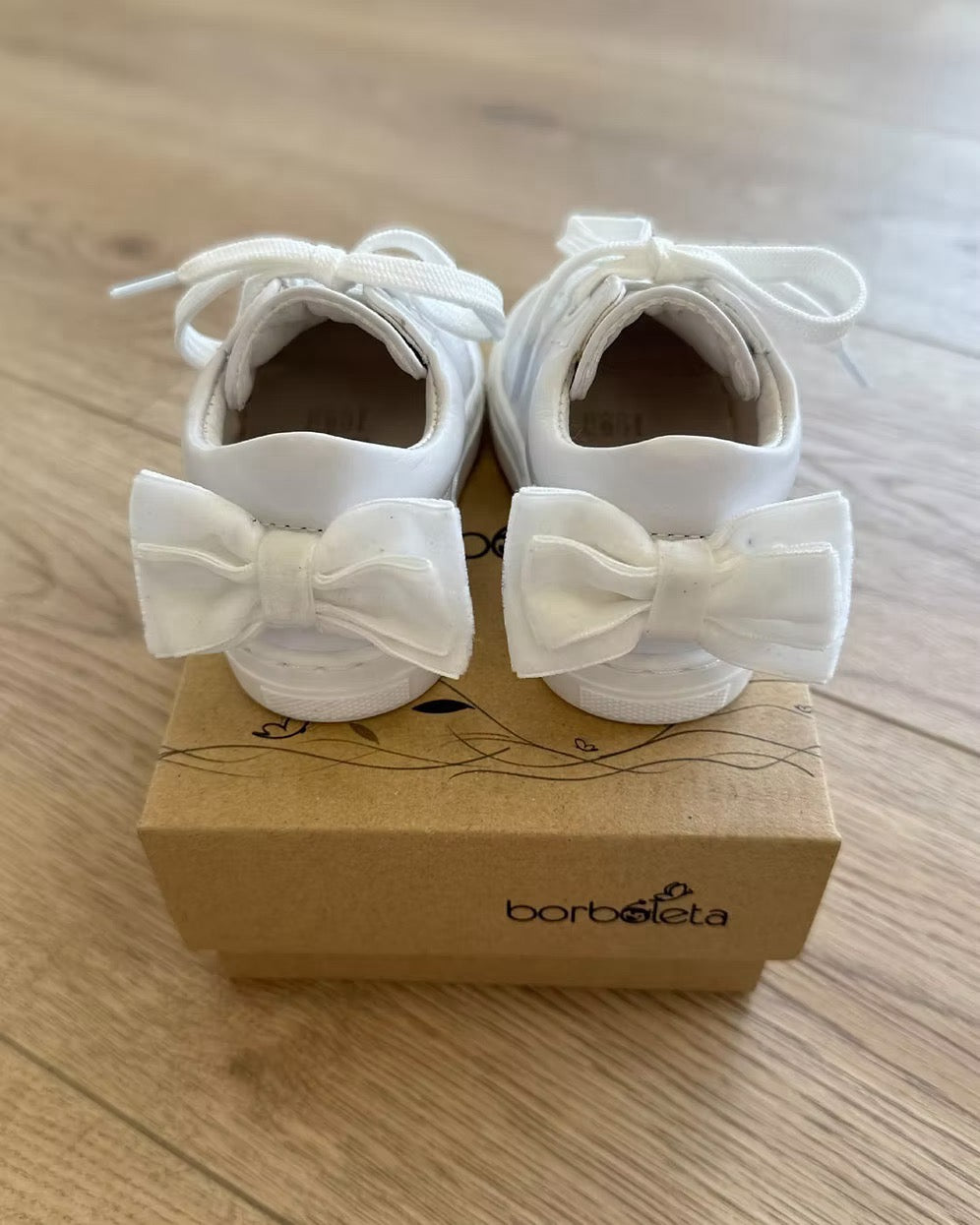 Borboleta Sara Bow Trainers featuring white leather, double velvet bows at the back, stitched rubber sole and classic lace-up design.