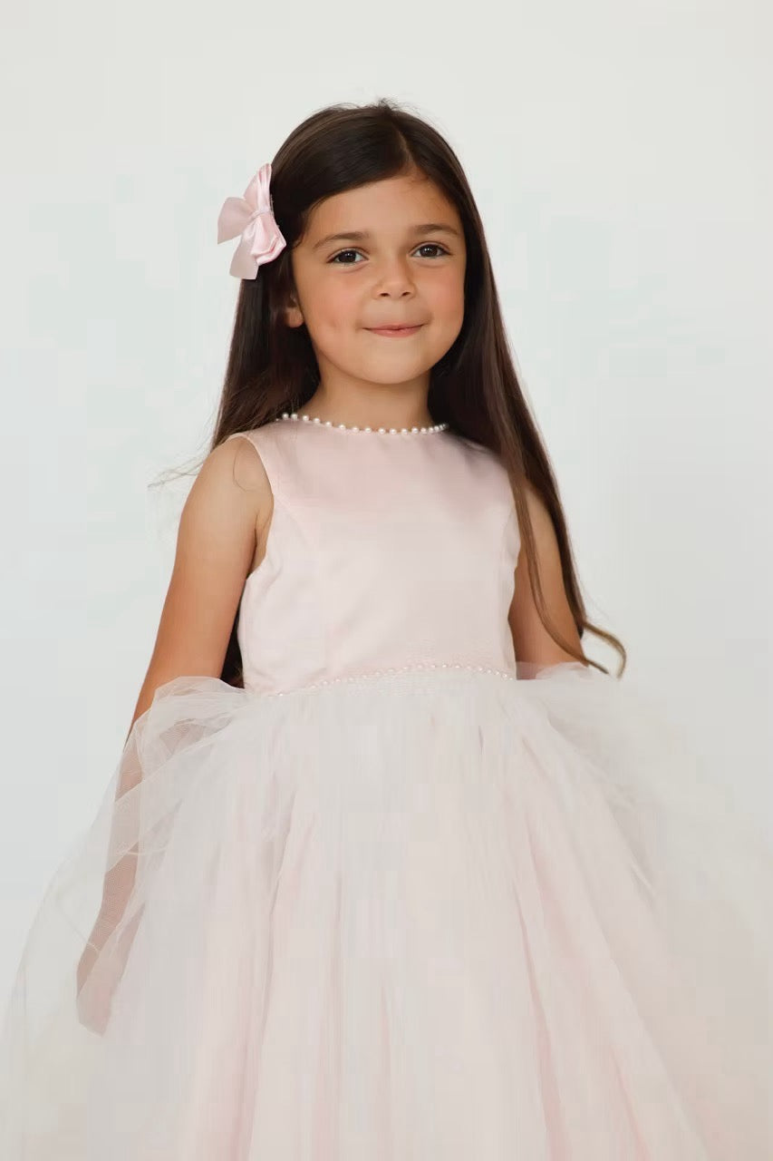 Sarah Louise Peach Pearl Ballerina Dress featuring a soft peach tone, pearl-trimmed neckline, full layered tulle skirt and statement V-back bow.