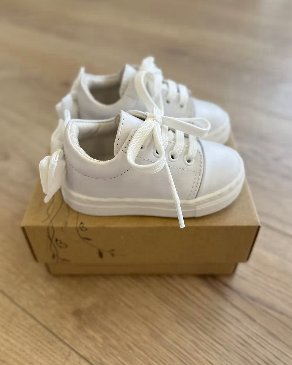 Borboleta Sara Bow Trainers featuring white leather, double velvet bows at the back, stitched rubber sole and classic lace-up design.