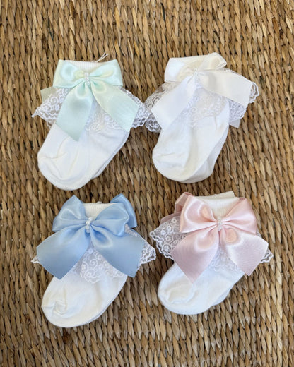Crafted in soft white fabric, each pair features a delicate lace frill trim, finished with a pretty satin side bow and elegant pearl chain centre.